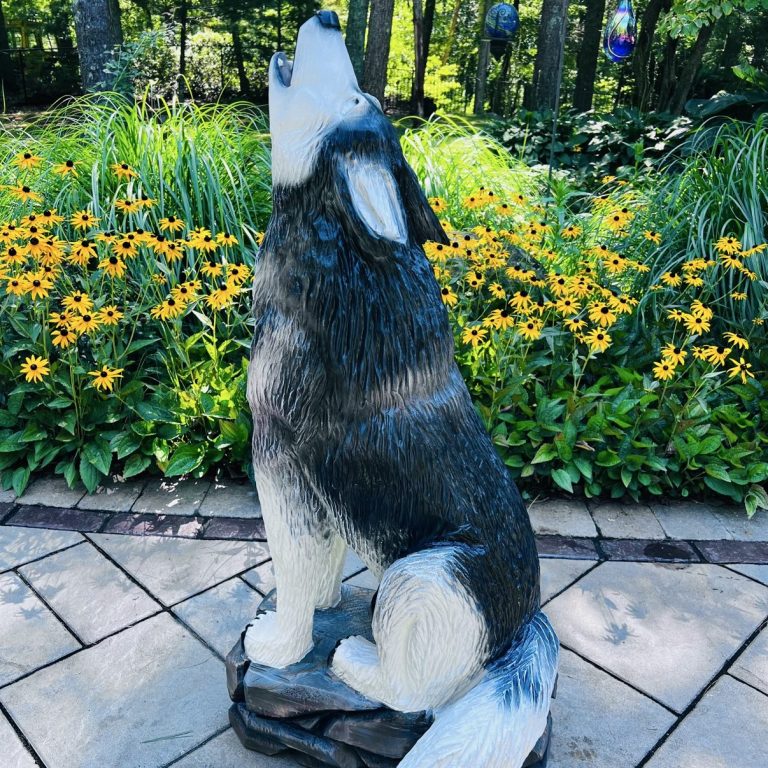 Howling wolf carving, painted finish, on a stone base