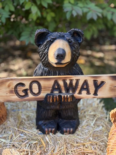 Bear holding reversible Welcome Go Away sign